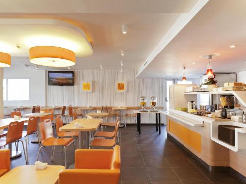 a restaurant with tables and chairs and a bar at ibis budget Hotel Brussels Airport in Diegem