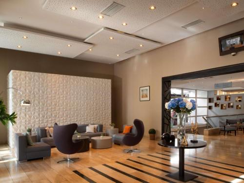 a lobby with a waiting room with couches and chairs at Novotel Santiago Vitacura in Santiago