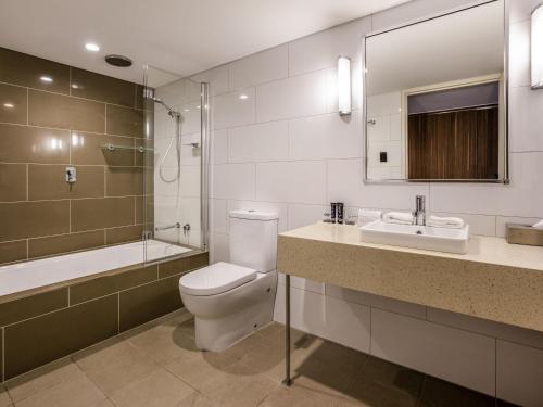 a bathroom with a toilet and a sink and a tub at Mantra Gladstone in Gladstone