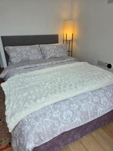 a large bed with a white comforter and a lamp at Bee Hive Studio Flat in Manchester