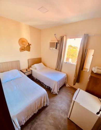 a hotel room with two beds and a window at Pousada Berro do Bode in Cabaceiras
