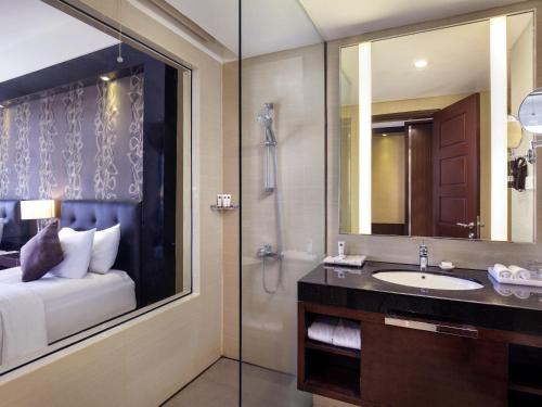 a bathroom with a bed and a sink and a shower at Grand Mercure Solo Baru in Solo