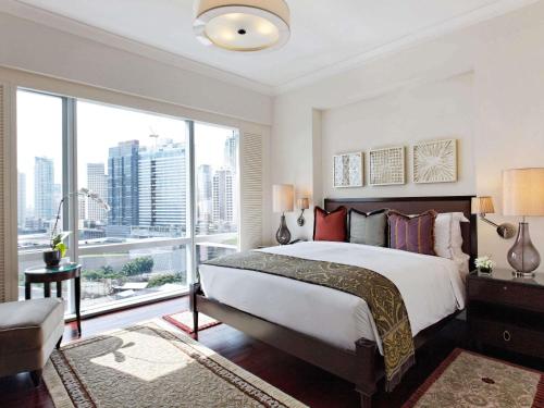 une chambre avec un grand lit et une grande fenêtre dans l'établissement Raffles Makati, à Manille