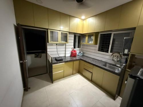 een kleine keuken met gele kasten en zwarte aanrechtbladen bij 2BHK Galaxy Height Shree Nagar Nagpur in Nagpur