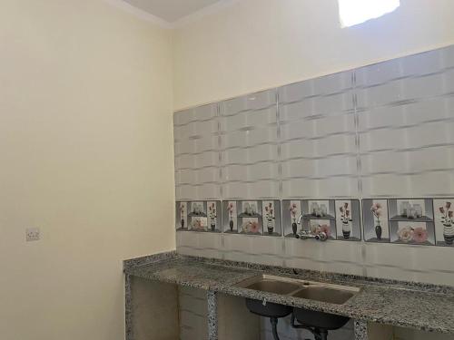 a bathroom with two sinks and pictures on the wall at هوستل خدمه مبيت in Disah