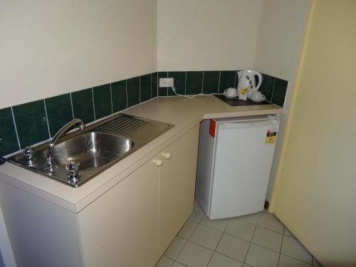 a small kitchen with a sink and a refrigerator at Sanno Marracoonda Perth Airport Hotel in Perth