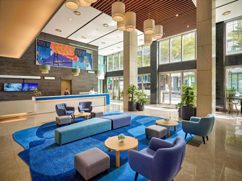 a lobby with a blue couch and chairs and tables at Novotel Living Saigon South in Ho Chi Minh City