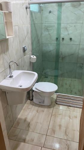 a bathroom with a toilet and a sink and a shower at Pousada Coqueiros in Delfinópolis