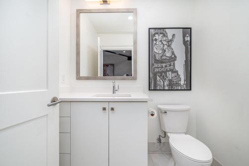 a white bathroom with a toilet and a mirror at The Saddlery - Mic Drop - Walk to Broadway in Nashville