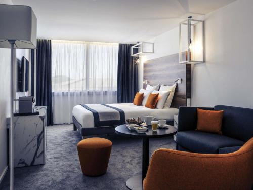 a hotel room with a bed and a couch and a table at Mercure Nancy Centre Gare in Nancy