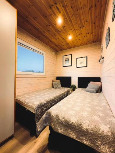 two beds in a small room with a window at Charmful Sunset Cabin - Private Hot Tub & Sauna - Beach access in Wapnica