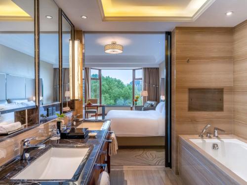 a bathroom with a bed and a tub and a sink at Sofitel Hangzhou Westlake - Few steps to West Lake, with panoramic lake view terrace in Hangzhou