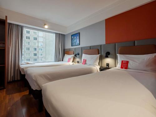 a hotel room with three beds and a window at ibis Guarulhos Aeroporto in Guarulhos