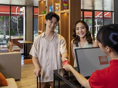 Ein Mann und eine Frau stehen vor einem Computer in der Unterkunft ibis Chiang Mai Nimman Journeyhub in Chiang Mai