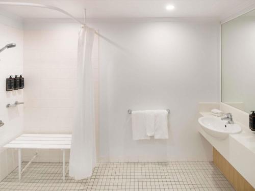 a white bathroom with a shower and a sink at Mercure Sydney Macquarie Park in Sydney