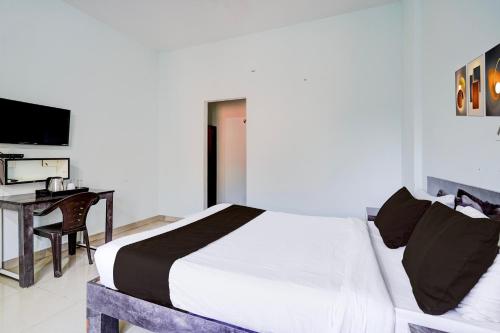 a bedroom with a bed and a desk and a television at Super Collection O Uttarahalli in Bengaluru