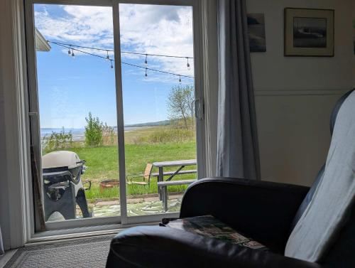 a living room with a sliding glass door with a view at Condo 1 - Waterfront with SPA Fireplace & Barbecue in Sainte-Anne-de-Beaupré