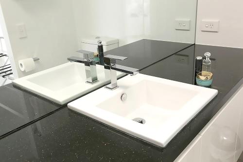 a bathroom with a white sink in a black counter at Cairns Aquarius in Cairns