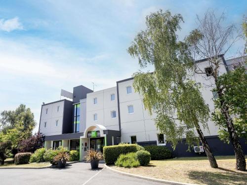 a large white building with a parking lot at Ibis Styles Cognac in Châteaubernard