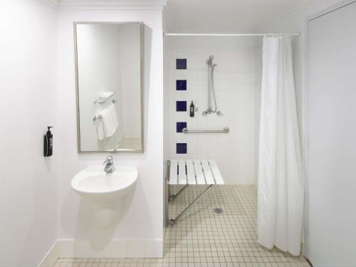 a white bathroom with a sink and a shower at Mercure Sydney Manly Warringah in Sydney