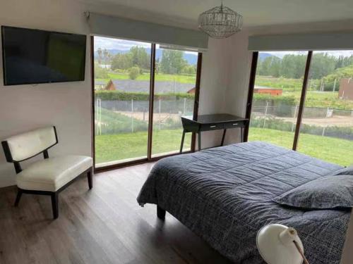 a bedroom with a bed and a chair and a large window at Casa vista Lago Rapel in Las Cabras