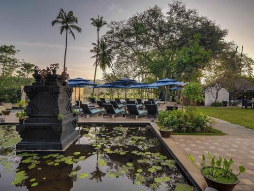 a fountain with chairs and a pond with water lilies at Novotel Goa Resort & Spa Candolim in Candolim