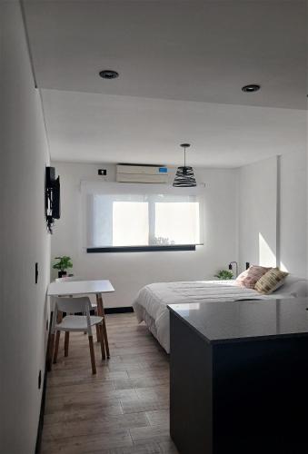 a white bedroom with a bed and a table at Departamento 9 de Julio Temperley in Turdera