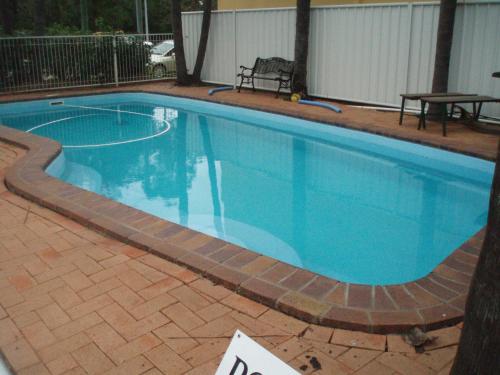 a pool in front of a house with a tennis racket at Dalby Parkview Motel in Dalby