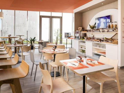 Un restaurante con mesas y sillas en una habitación. en Aparthotel Adagio Access Paris Massy Gare, en Massy