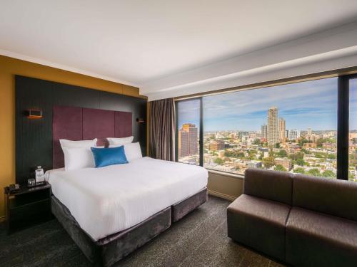 a hotel room with a bed and a large window at Pullman Sydney Hyde Park in Sydney