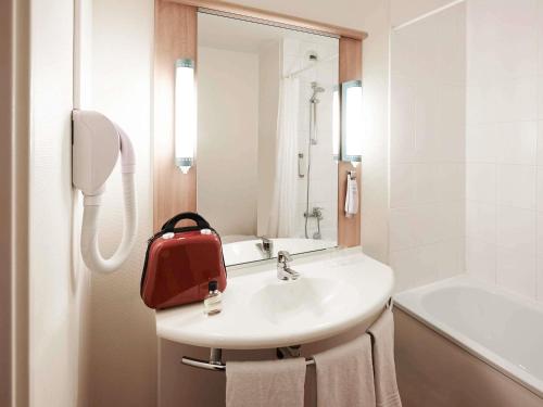 a bathroom with a sink with a red bag on it at ibis Nancy Centre Gare et Congres in Nancy