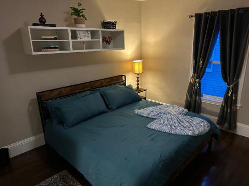 Un dormitorio con una cama con sábanas azules y una ventana. en Spacious 3 Bedroom Near Train Station, en Malden