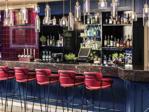 a bar with red bar stools in a room at Mercure Swansea Hotel in Swansea