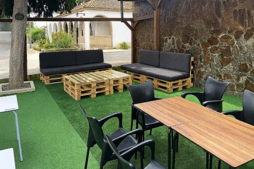 a patio with two benches and tables and green grass at HOSTAL LAS PALOMAS in Lucena