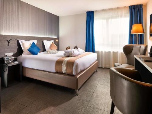 a hotel room with a large bed and a chair at Mercure Bale Mulhouse Aeroport in Blotzheim