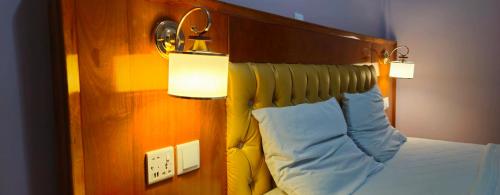 a bed with a wooden headboard and two lights on it at Rockville Building Studio Meuble Guest House in Yaoundé