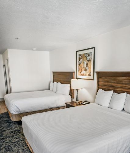 two beds in a hotel room with white sheets at Crystal Inn Hotel & Suites - Salt Lake City in Salt Lake City