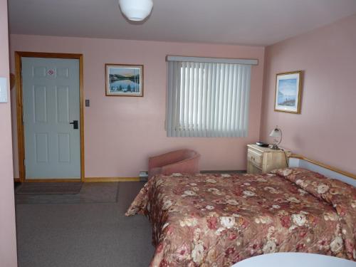 a bedroom with a bed and a window and a door at motel nolen in Saint-Siméon