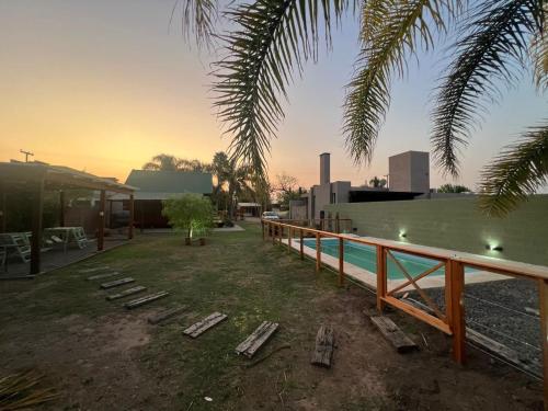 a backyard with a pool and a fence and a building at Cabaña con pileta & jardín- a minutos del centro y la playa in Miramar