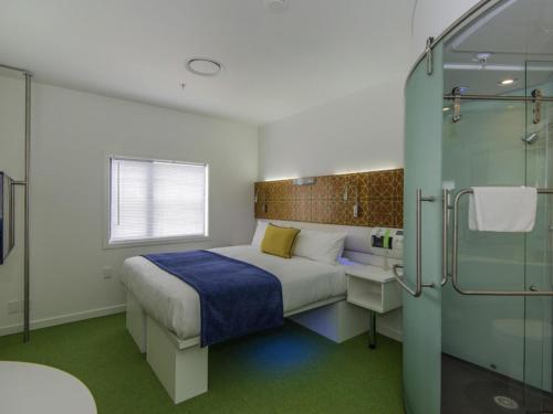 a bedroom with a bed and a glass shower at BreakFree on Cashel, an Accor Hotel in Christchurch