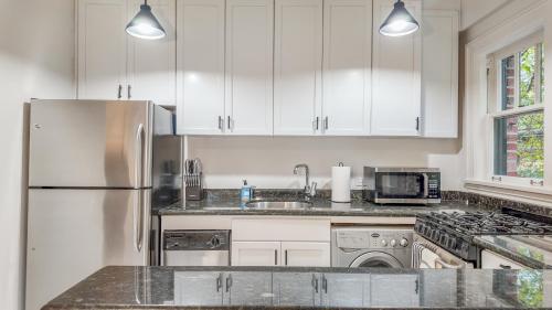 a kitchen with white cabinets and a stainless steel refrigerator at Let's Get Cozy In Seattle! in Seattle