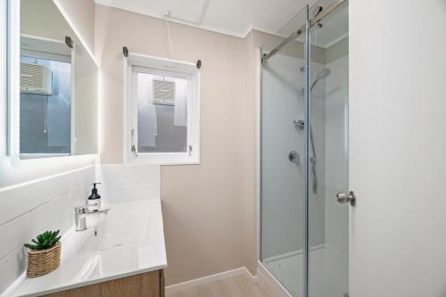 a white bathroom with a shower and a sink at 5 Bedrooms Lake View Cosy Place in Rotorua
