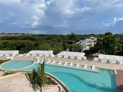 a large swimming pool with white umbrellas and the ocean at apartamento exclusivo con jacuzzi, piscina y vista al lago in Las Terrenas