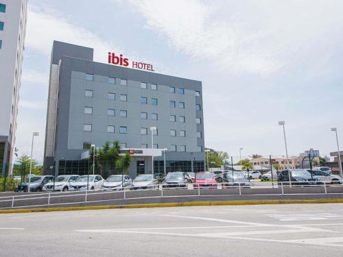 a big building with cars parked in a parking lot at Ibis Guaratingueta Aparecida - Circuito da Fé in Guaratinguetá