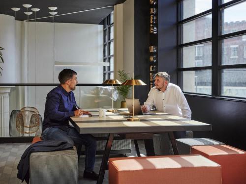 two men sitting at a table in a restaurant at Aparthotel Adagio Liverpool City Centre in Liverpool