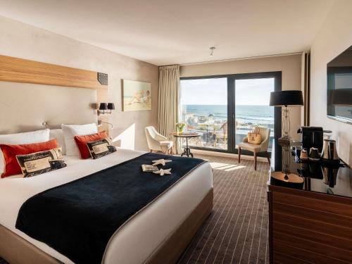 Una habitación de hotel con una cama grande y una ventana grande. en Côte Ouest Thalasso & Spa Les Sables d'Olonne - MGallery Collection, en Les Sables-dʼOlonne