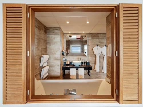 Un baño con un gran espejo y un lavabo. en Côte Ouest Thalasso & Spa Les Sables d'Olonne - MGallery Collection, en Les Sables-dʼOlonne