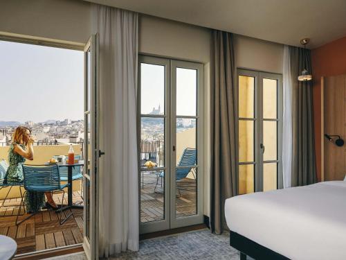 a hotel room with a bed and a view of a balcony at Mercure Marseille Canebière Vieux-Port in Marseille