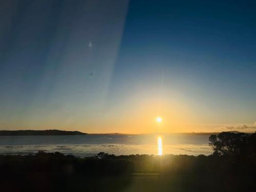 a sunset over a body of water with the sun in the sky at Auckland Sunrise Sea View in Auckland