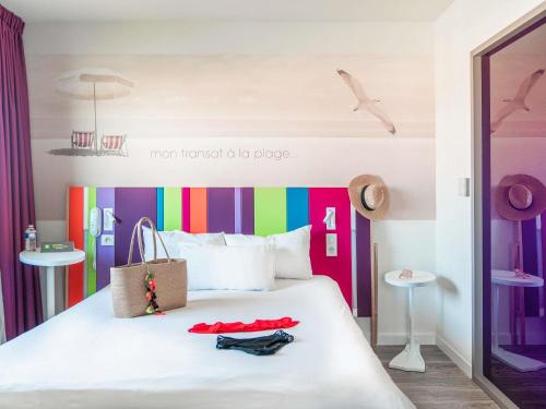 1 dormitorio con 1 cama con cabecero colorido en ibis Styles Les Sables Olonne, en Les Sables-dʼOlonne